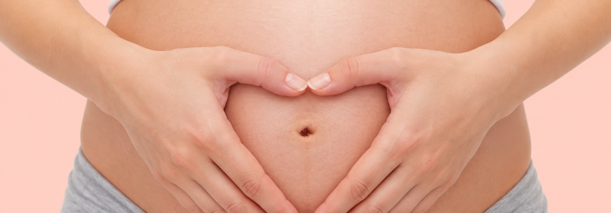 Pregnant woman forming a heart shape with her hands over her baby bump