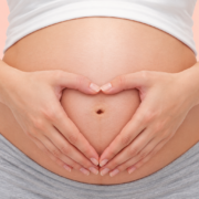 Pregnant woman forming a heart shape with her hands over her baby bump